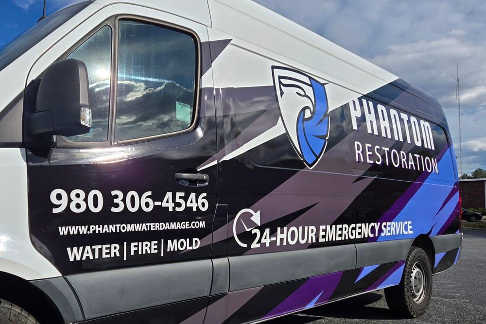 A Phantom Restoration van door listing water, fire and mold and 24-hour emergency service
