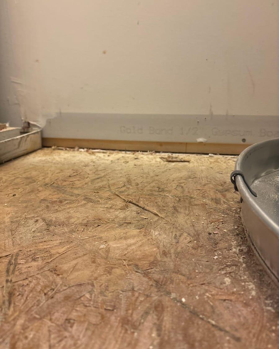 A room with the drywall cut away along the floor and the subfloor exposed