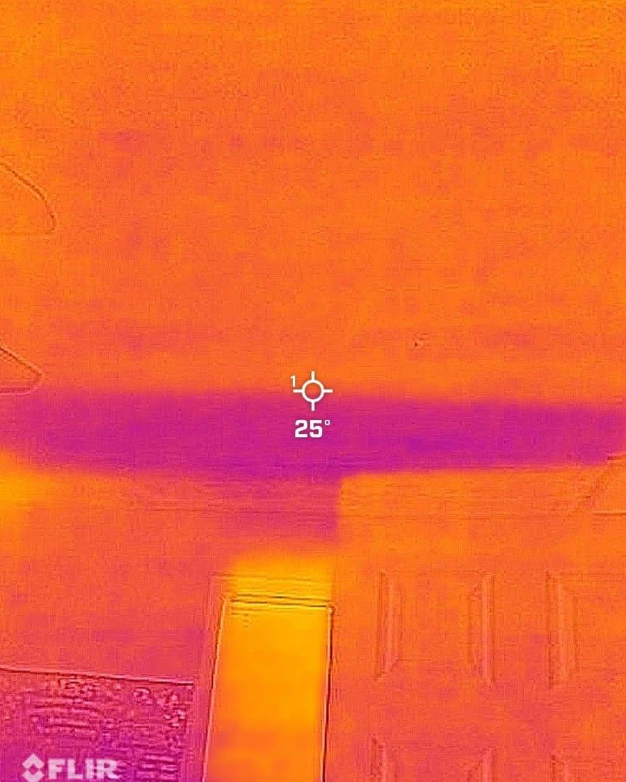 A thermal camera image showing a cool band of moisture above a doorway