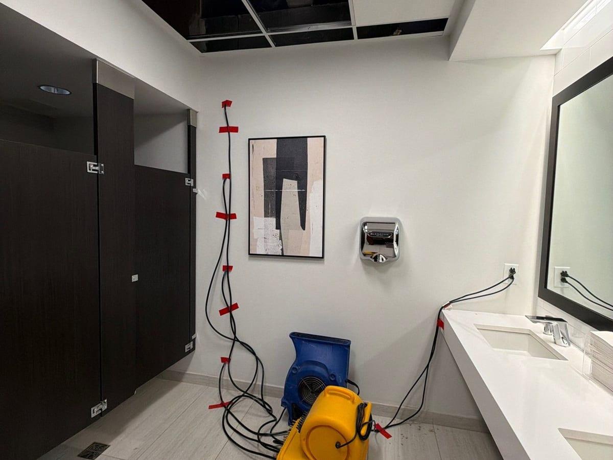 A dehumidifier and air movers drying a commercial restroom