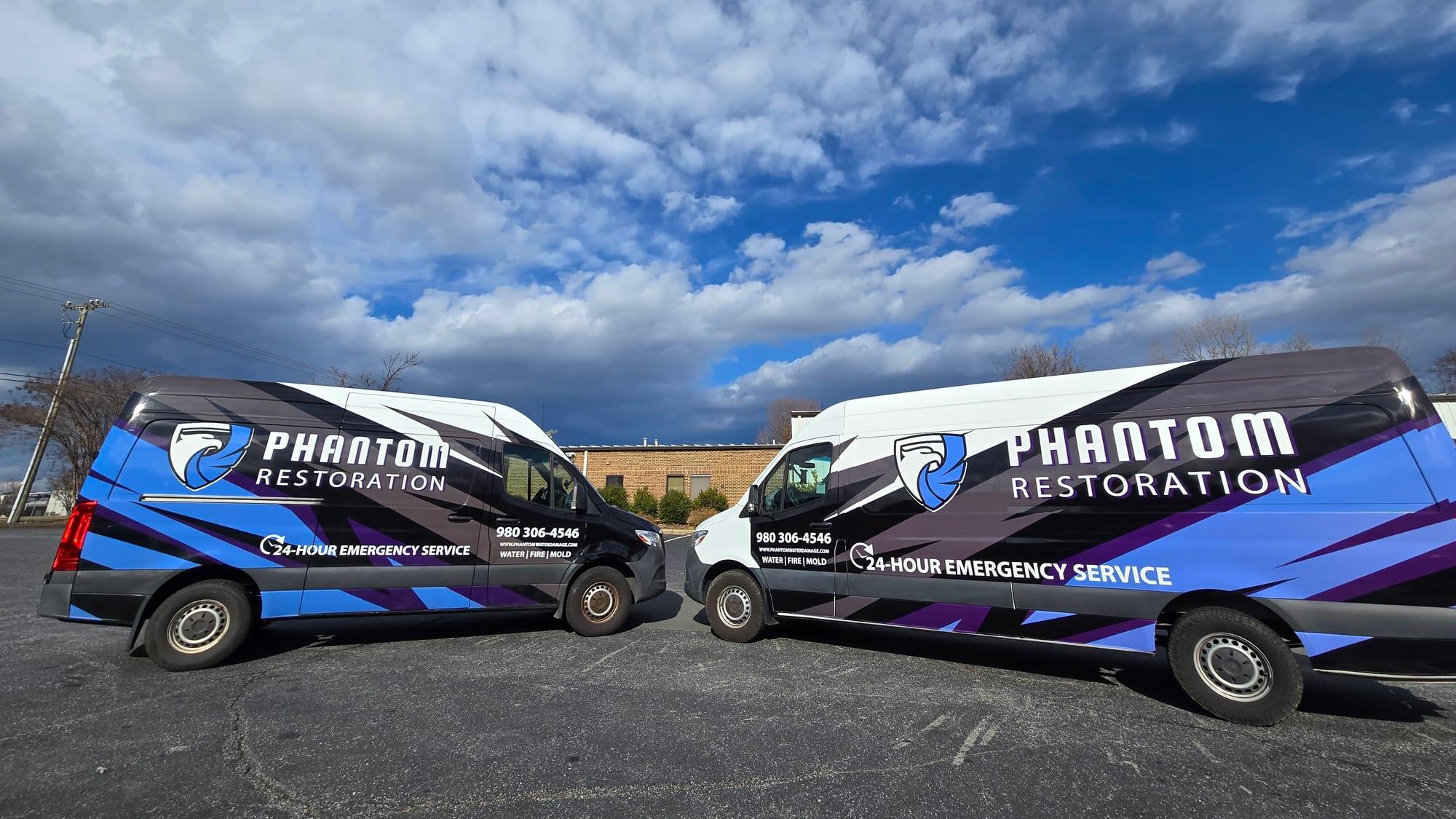 Two branded Phantom Restoration vans parked nose to nose