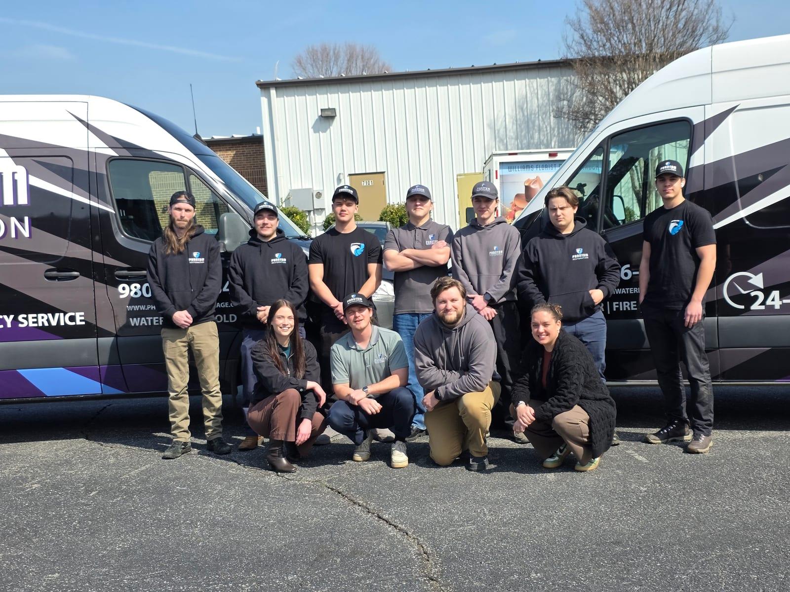 The Phantom Restoration team standing together between two branded vans
