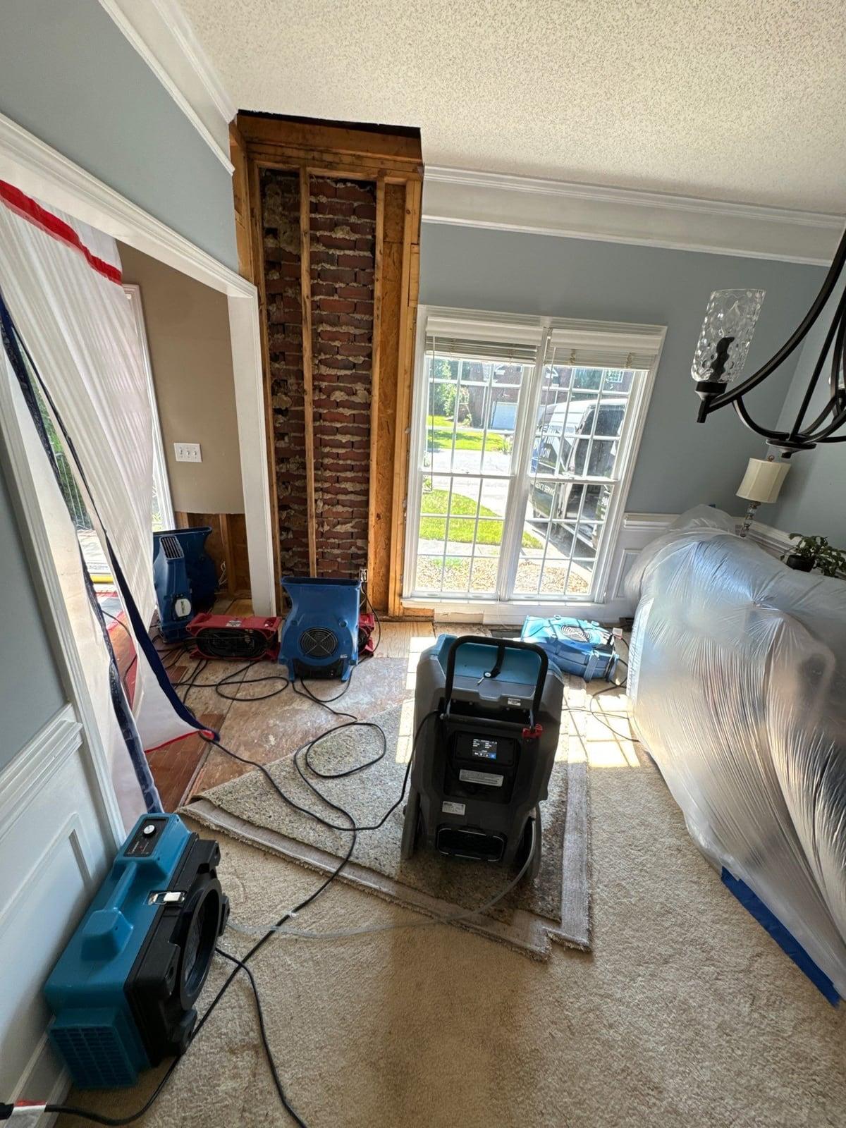 Air movers and a dehumidifier drying an opened wall in a home