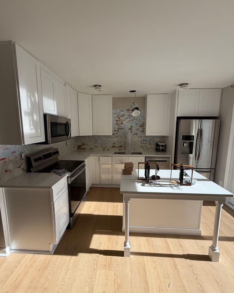The same kitchen rebuilt with white cabinets, an island and a new floor