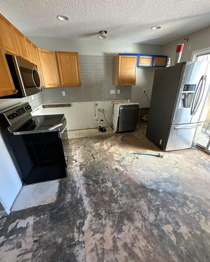 A kitchen with the flooring taken up and the subfloor exposed after water damage