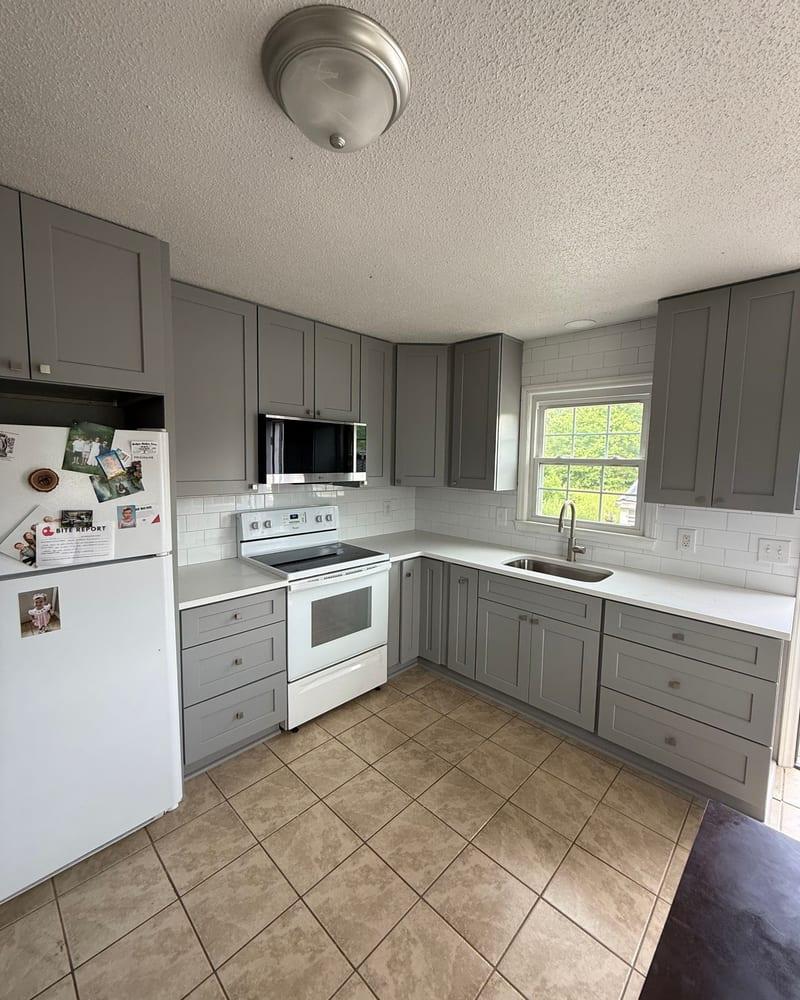 The rebuilt kitchen with gray cabinets and a tile floor