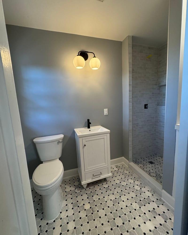 The rebuilt bathroom with a new vanity, shower and patterned tile floor