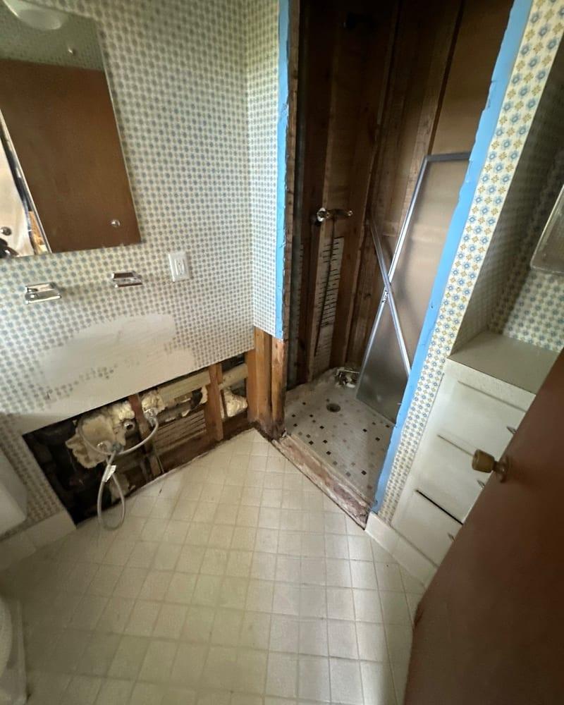 A bathroom wall opened at the shower plumbing to dry the framing