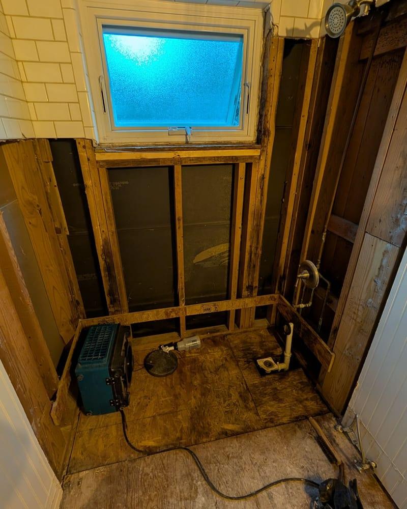 A bathroom opened to the framing with the damaged subfloor exposed
