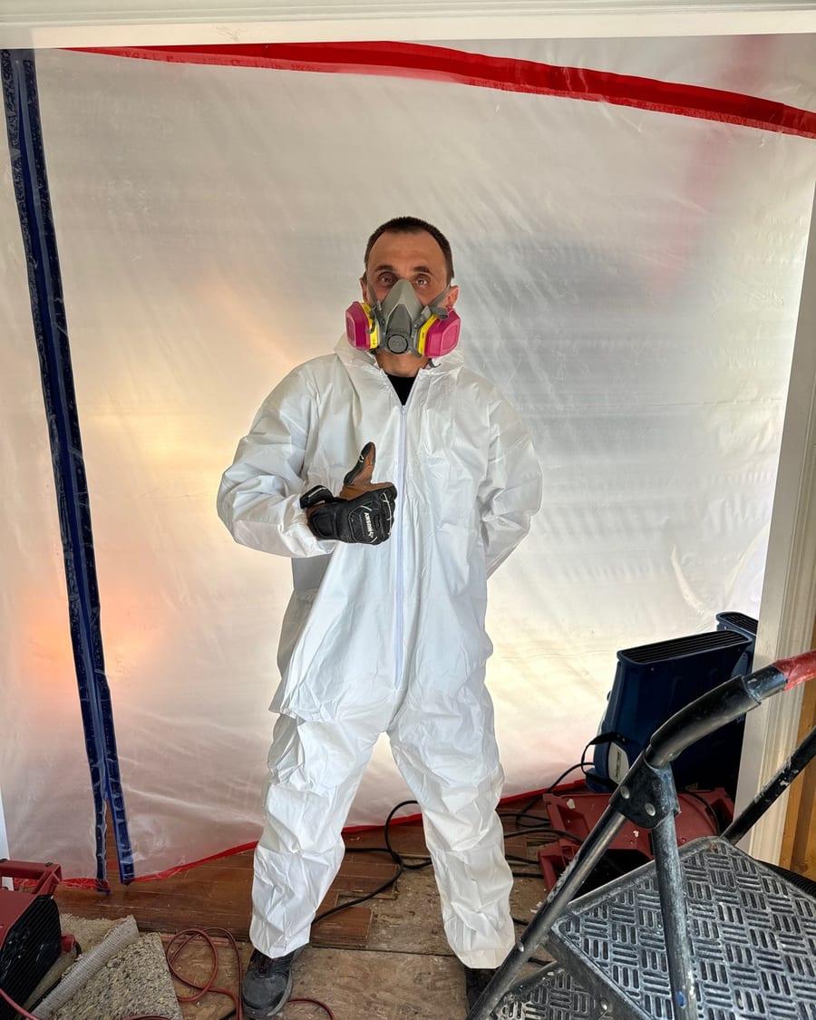 A Phantom Restoration technician giving a thumbs-up inside a sealed work area with drying equipment
